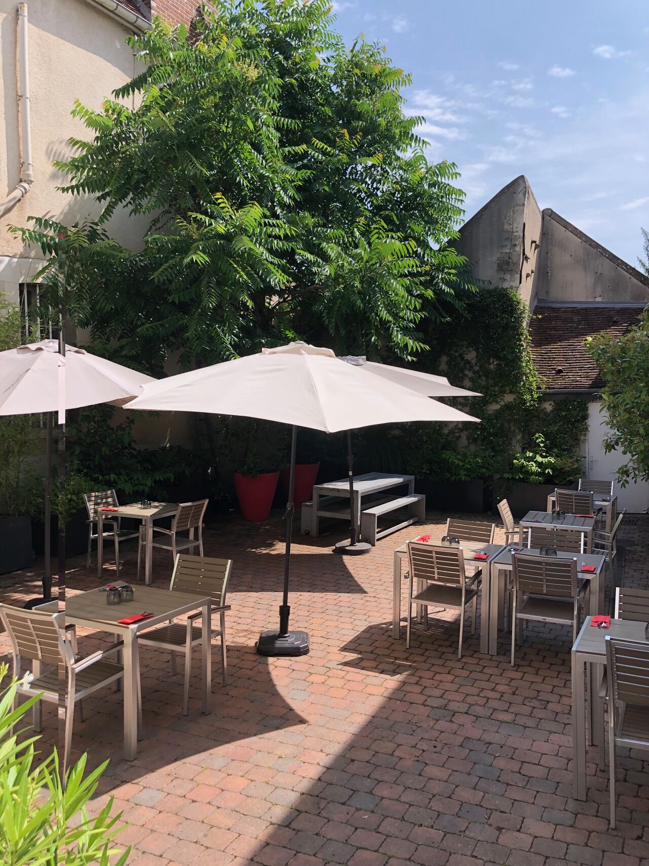 La terrasse ensoleillée d'À Côté du Saint Martin, cour pavée et parasols en plein centre d'Auxerre